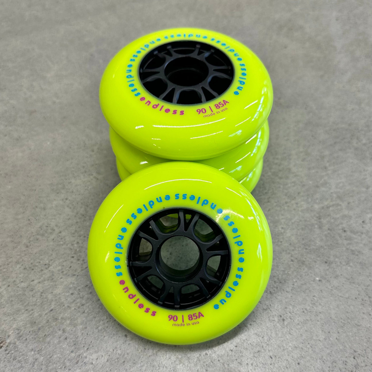 Endless Blading Co. 90mm 85A neon yellow inline skate wheels with black high-performance cores in a stack