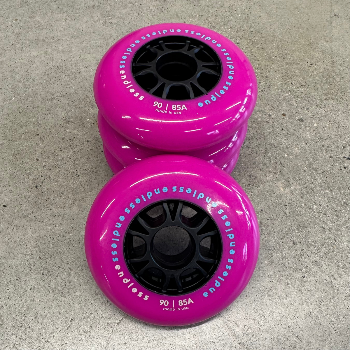 Endless Blading Co. 90mm 85A inline skate wheels in bright pink with black high-performance cores on concrete.