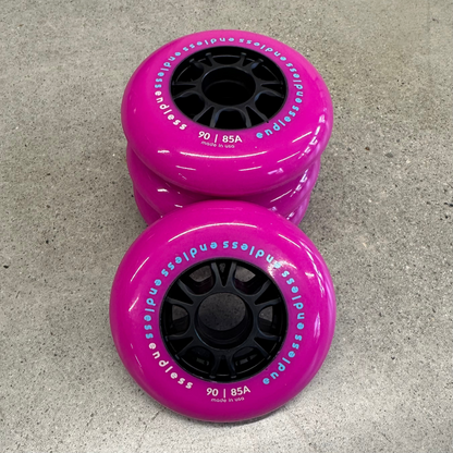 Endless Blading Co. 90mm 85A inline skate wheels in bright pink with black high-performance cores on concrete.