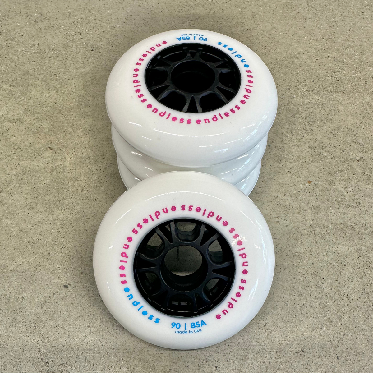 Endless Blading Co. 90mm 85A white inline skate wheels with black cores and pink and blue branding text