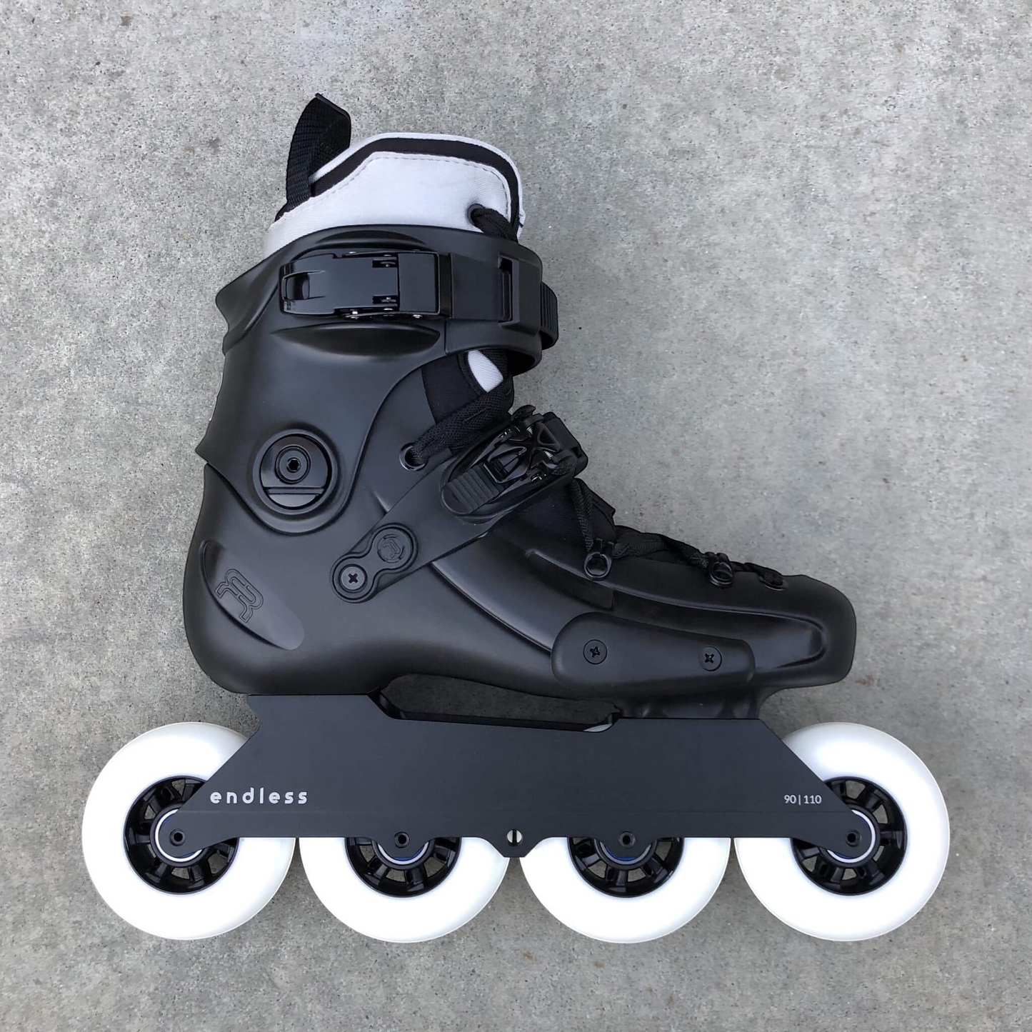 Endless Blading Co. 90 Classic Frame in black mounted on a black urban skate boot with four white wheels