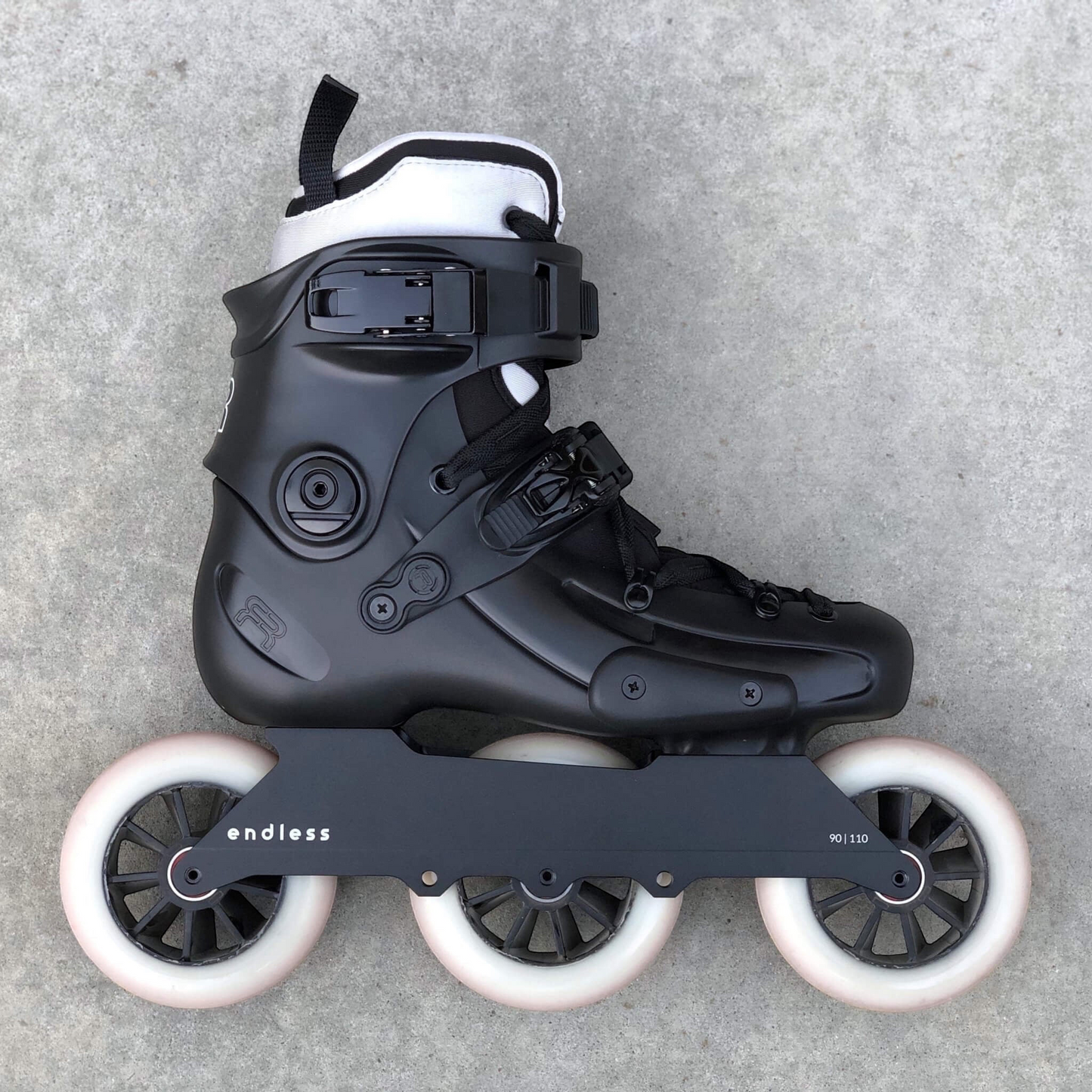 Endless Blading Co. 90 Classic frame in black mounted on a black urban skate boot with three white wheels.