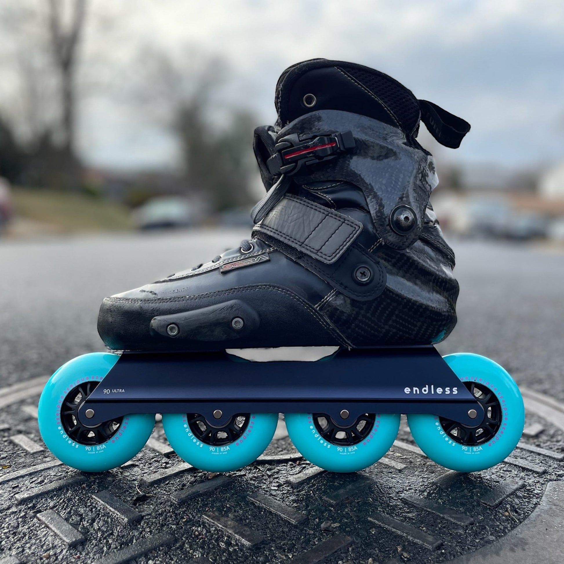 Endless Blading Co. Midnight Blue UFS inline skate frame with four bright turquoise 90mm wheels.