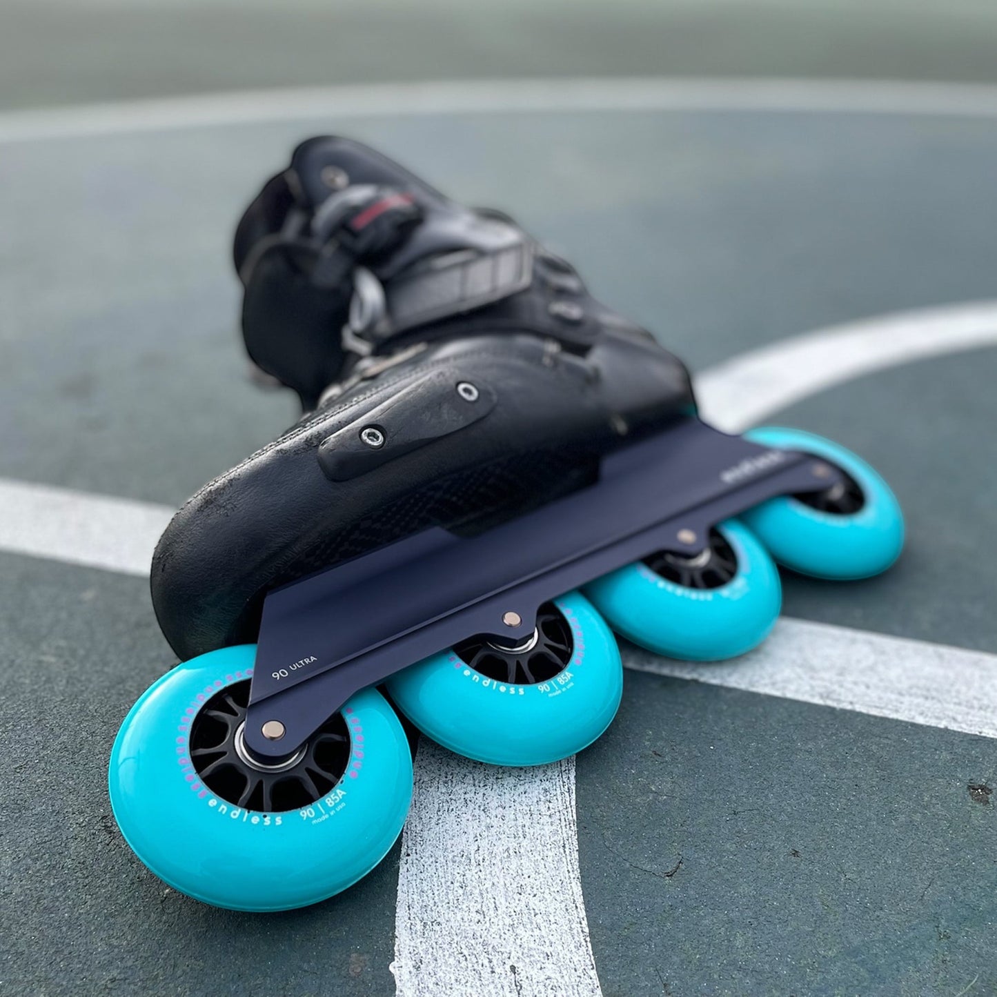Endless Blading Co. Midnight Blue UFS inline skate frame with four bright turquoise 90mm wheels.