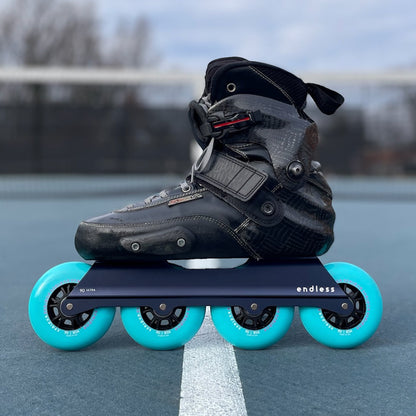 Endless Blading Co. Midnight Blue UFS inline skate frame with four bright turquoise 90mm wheels.