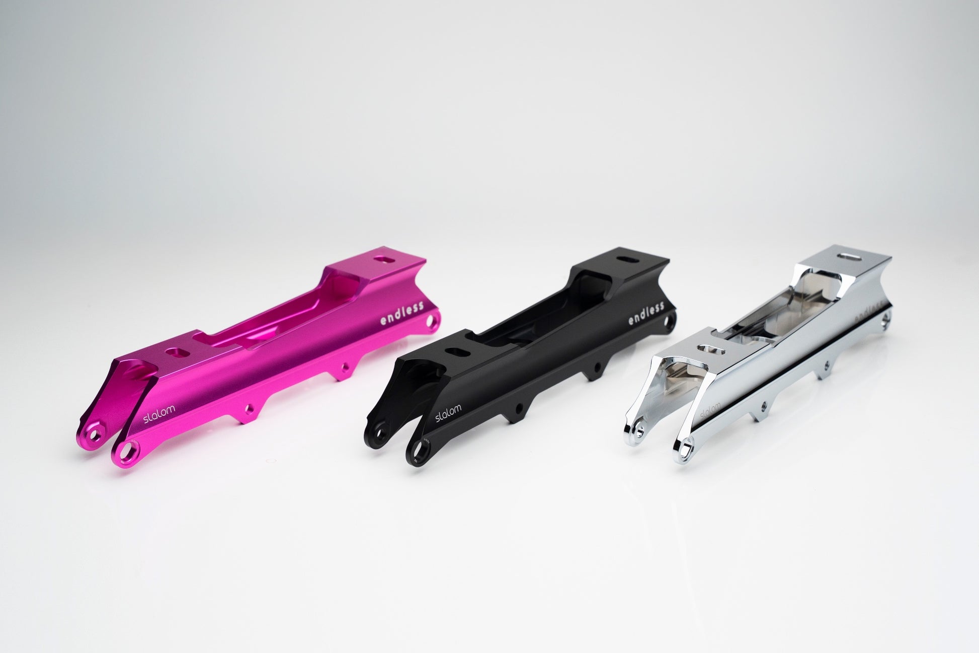 Endless Blading Co. pink, black, and chrome aluminum slalom frames with rocker axle options for freestyle skating.